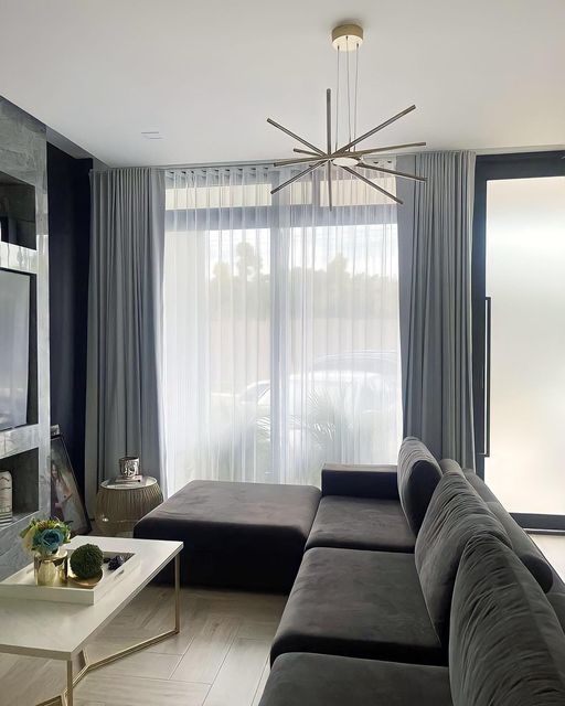 Modern living room with white ripplefold curtains showing smooth folds on wooden rod