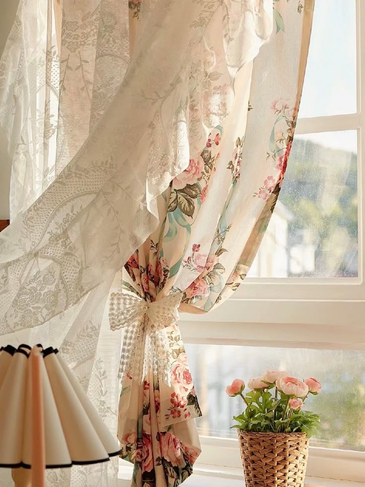 Sheer floral curtain tied with ribbon, sunlight, wicker basket with pink flowers on window sill