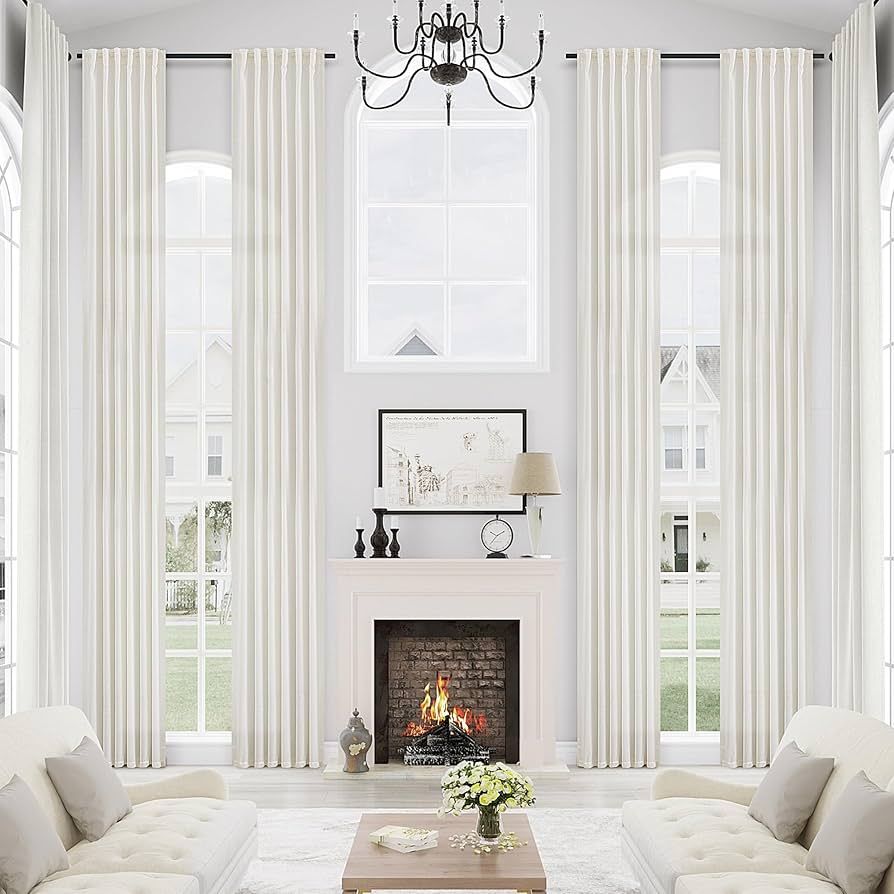 Bright living room with tall white blackout curtains, cozy sofas, fireplace, and chandelier.