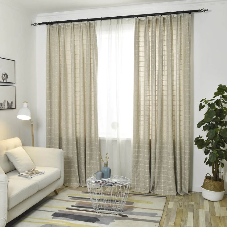 Beige grid-patterned blackout curtains on window in modern living room with sofa and plants