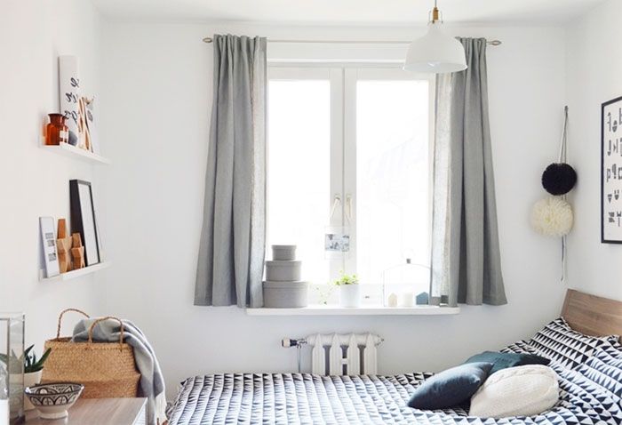 Modern bedroom with light gray blackout curtains on a large window, cozy bed, and minimalist decor