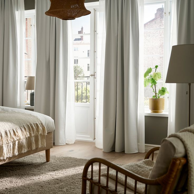 Modern bedroom with floor-to-ceiling white blackout curtains and natural light.