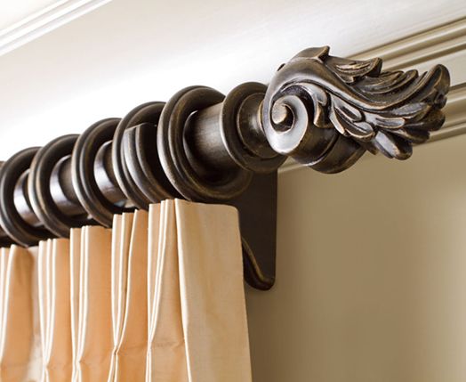 Elegant curtain track system with ornate finial and beige pleated blackout curtain installed