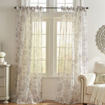 Sheer floral curtains on a rod over large windows in a bright living room