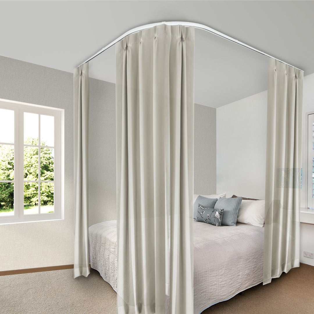 Ceiling-mounted curved curtain track with beige blackout curtains around a modern bed