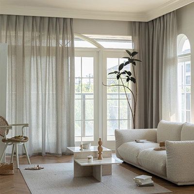 Modern living room with sheer curtains, white sofa, and large windows letting in natural light