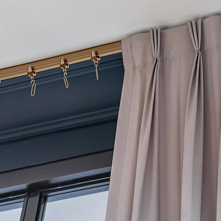 Ceiling-mounted curtain track system with pleated grey blackout curtain over window