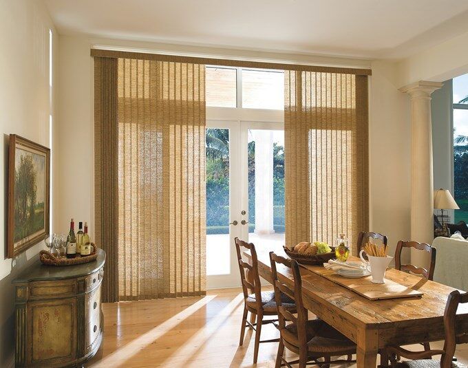 Beige vertical blinds on sliding glass doors in a bright dining room with rustic wooden table