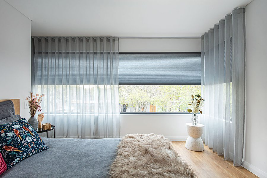 Modern bedroom with sheer grey curtains, blackout blinds, and minimalist decor