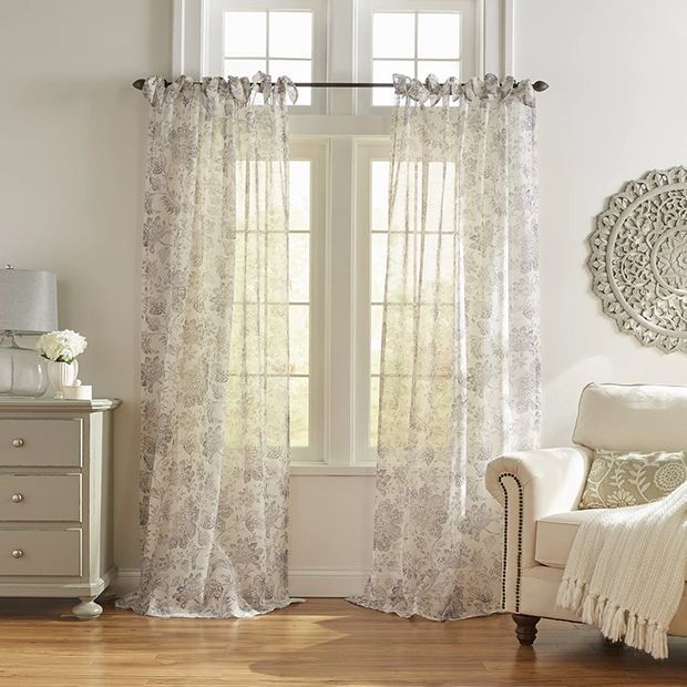 Light-filtering sheer floral curtains on tall windows in a cozy, sunlit living room