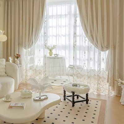 Elegant living room with sheer curtain panels, embroidered voile, and soft white furniture