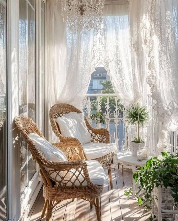 Sunlit balcony with sheer lace curtains, wicker chairs, green plants, and a chandelier