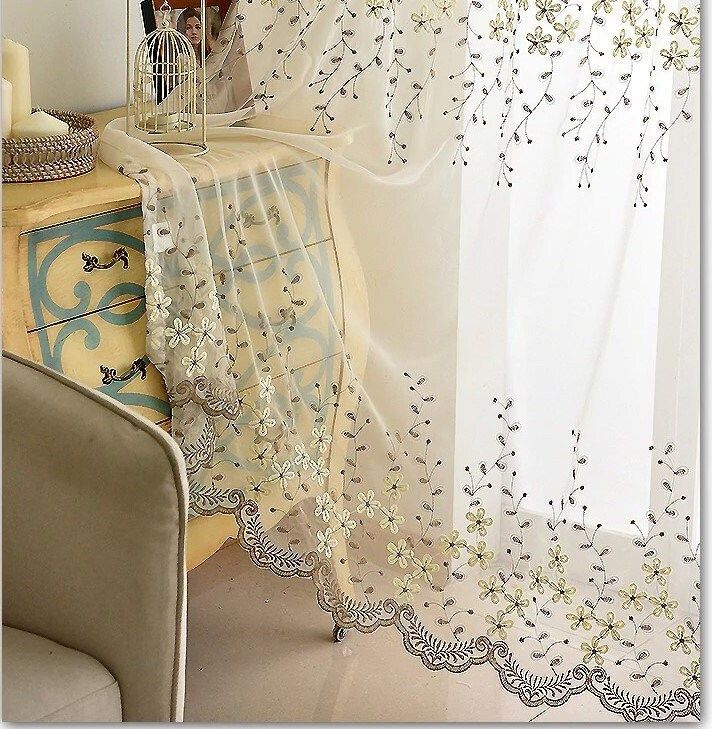 Sheer floral embroidered curtain panel draped over vintage table in cozy living room