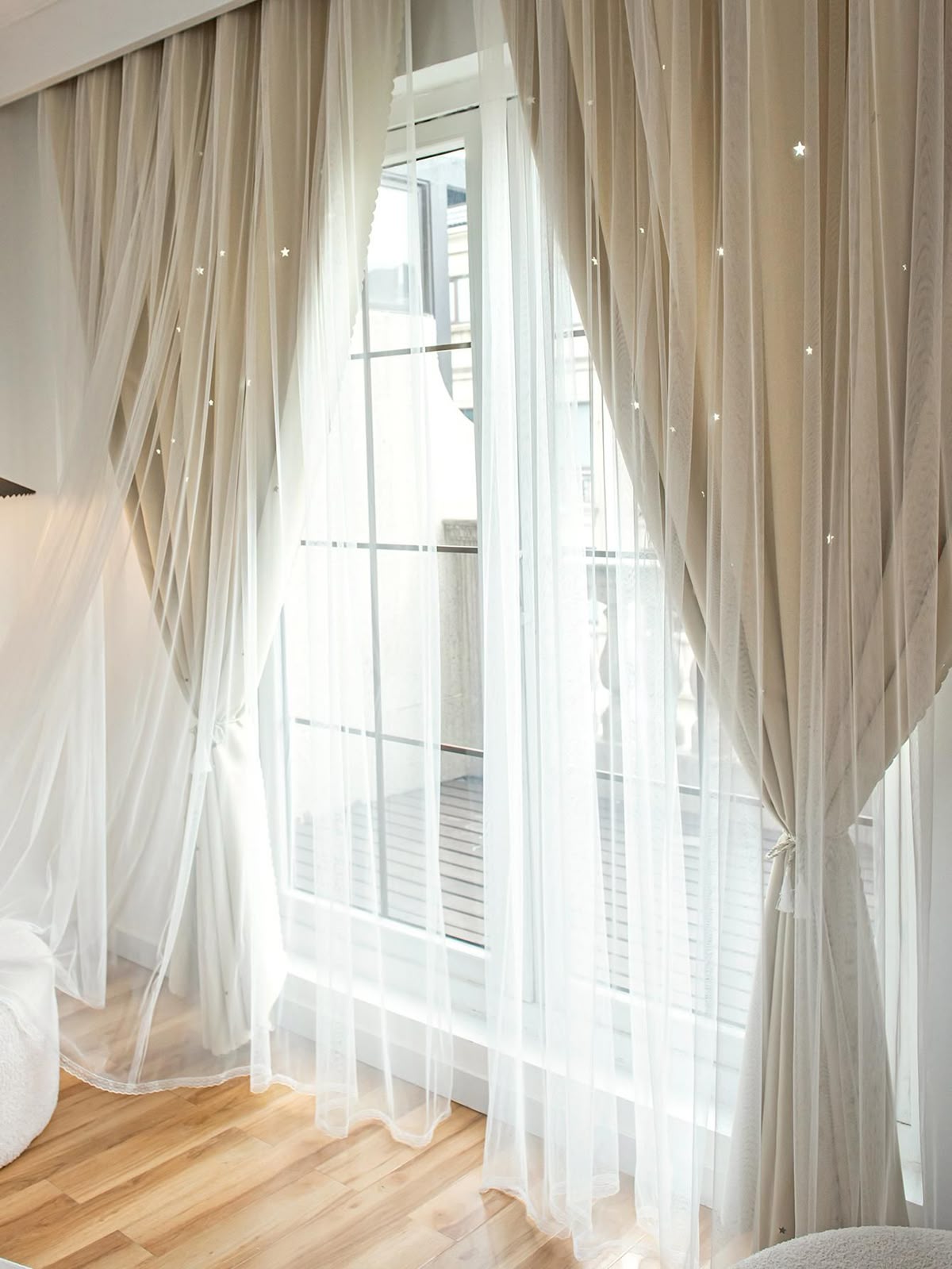 Elegant double-layer curtain system with sheer drapes and star cutouts on large window