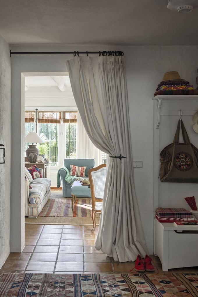 Cozy living space with floor-length cream blackout curtain and natural light, tile flooring, and colorful decor.