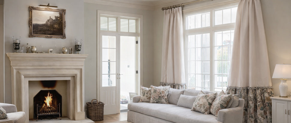 Elegant living room with large windows, ruffled blackout curtains, cozy sofa, and fireplace.