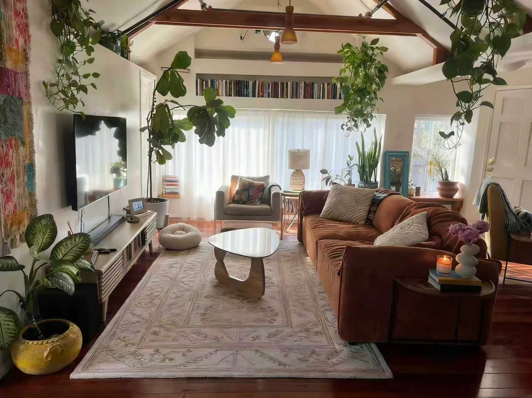 Bright living room with sheer curtain panels, modern sofa, lush houseplants, and cozy decor