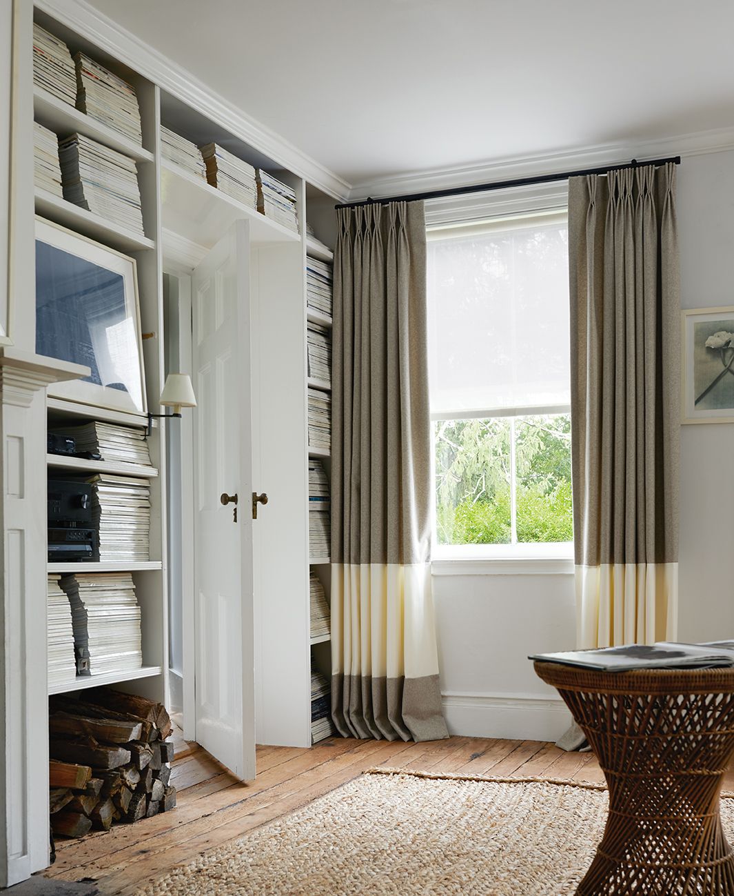 Cozy living room with pleated blackout curtains on window, wooden floor, and built-in bookshelf.