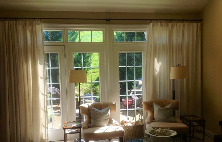 Bright living room with white blackout curtains, large French windows, and cozy armchairs