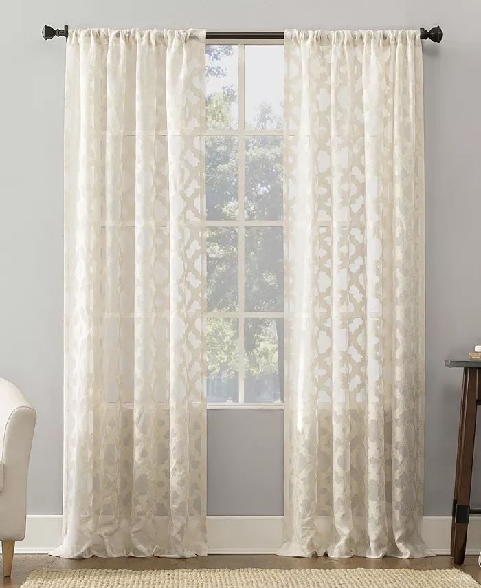 Sheer white patterned curtains on a window letting natural light into a modern living room.