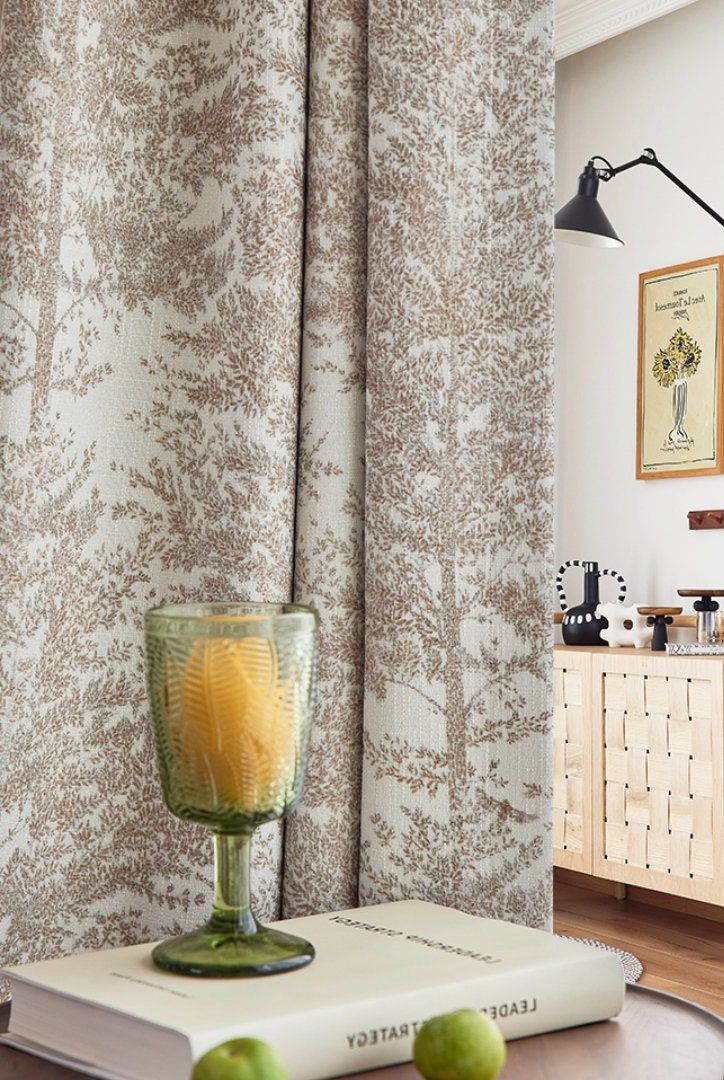 Neutral tree-patterned blackout curtain in cozy living room with glass, book, and modern decor
