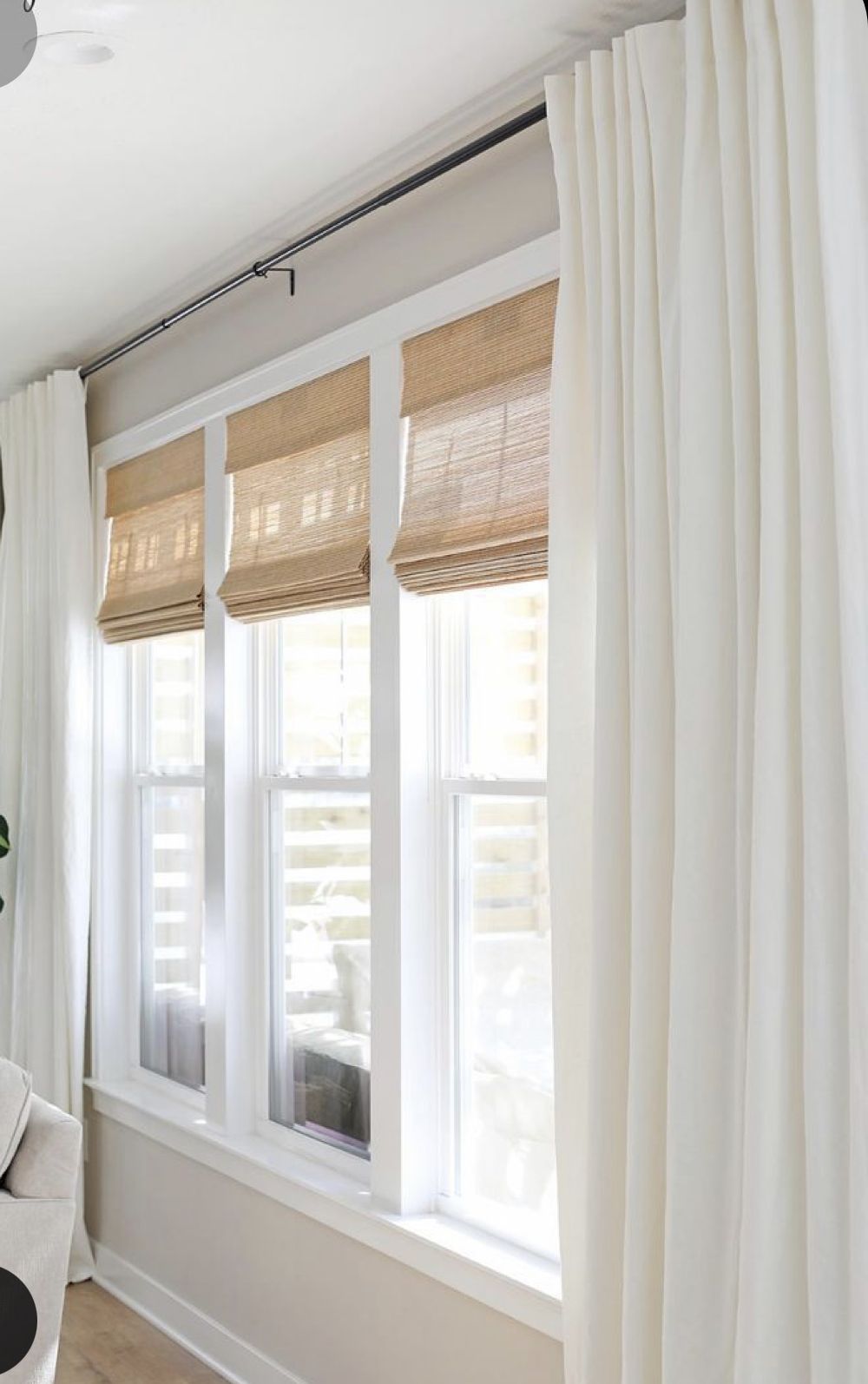 Modern living room windows with white blackout curtains and natural woven shades