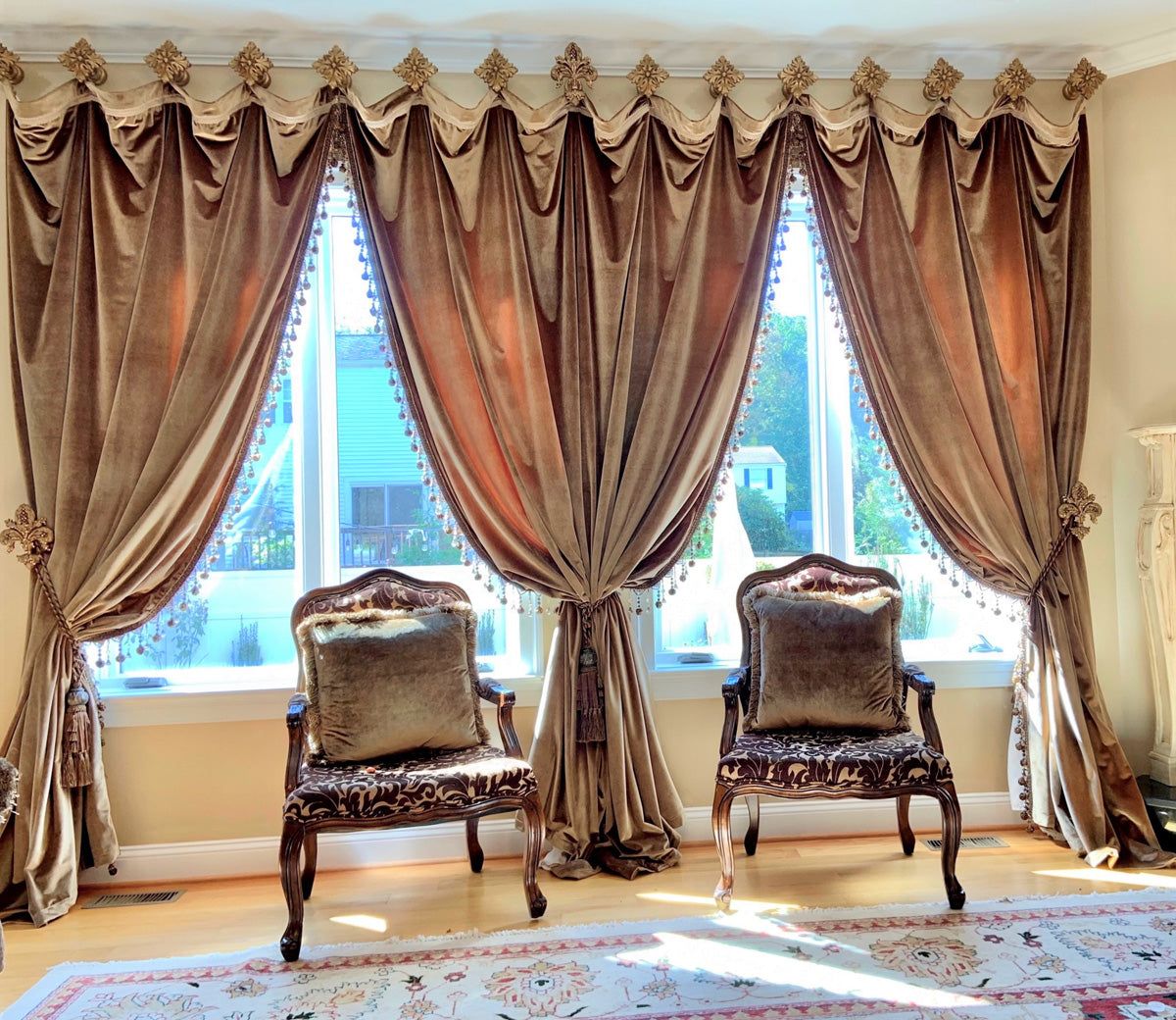 Elegant velvet blackout curtains with tassel trim and ornate wooden chairs in a sunlit living room