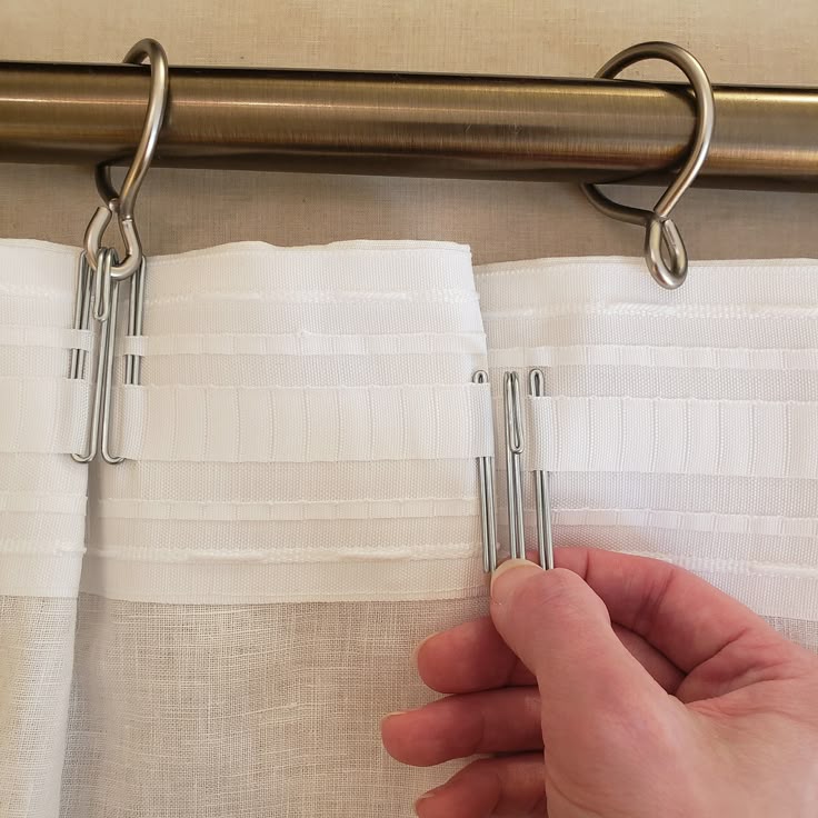 Silver adjustable tension rod installed inside window frame with white curtains