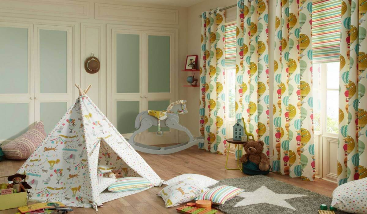 Playful kids’ room with whimsical patterned curtain panels, tipi tent, pillows, and rocking horse