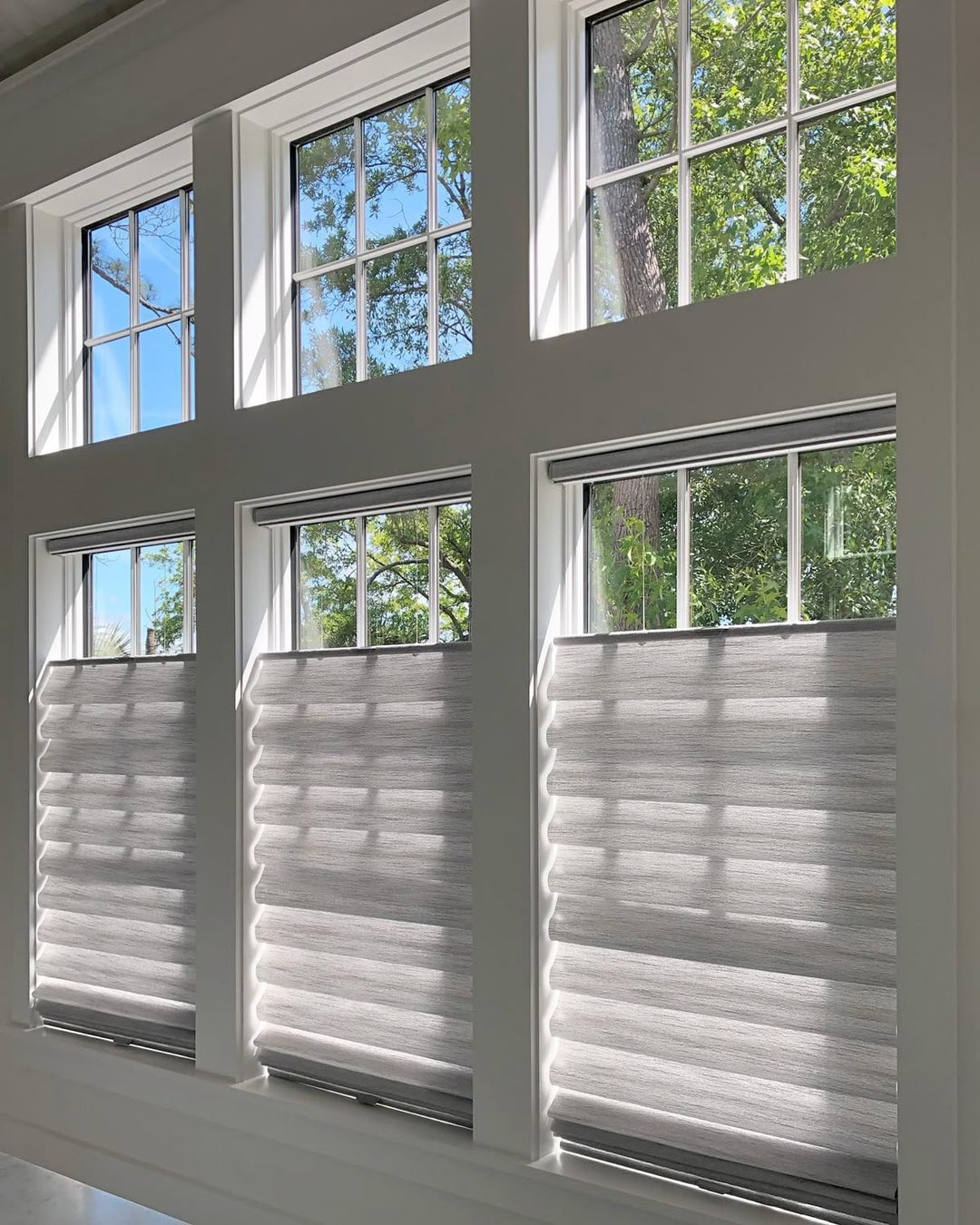Modern living room with large windows and gray pleated blackout shades partially drawn