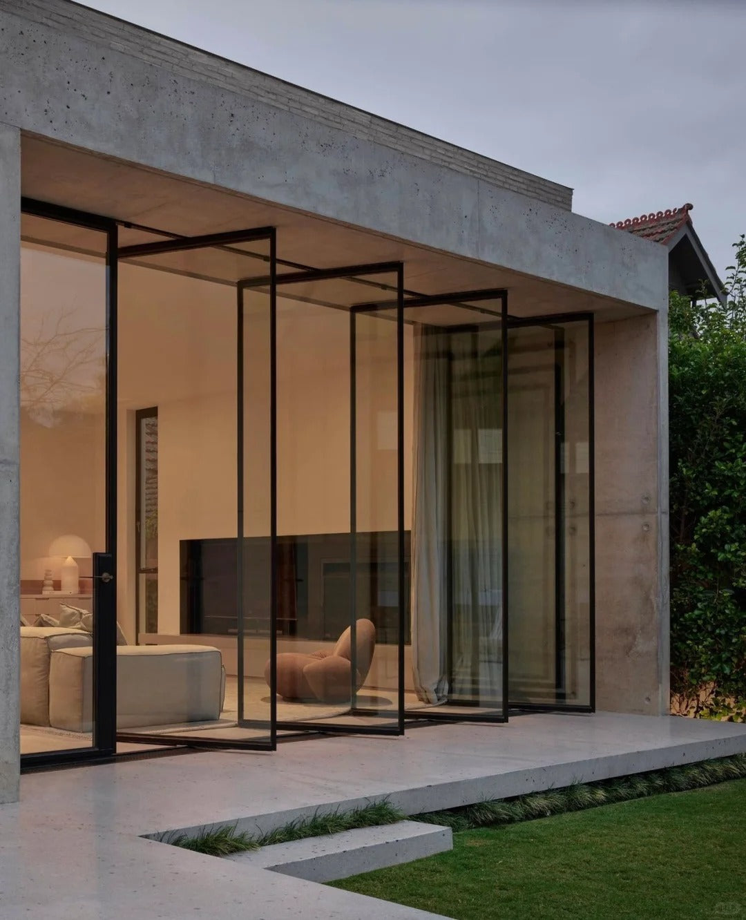 Modern living room with large glass sliding doors, floor-to-ceiling blackout curtains, and concrete patio.