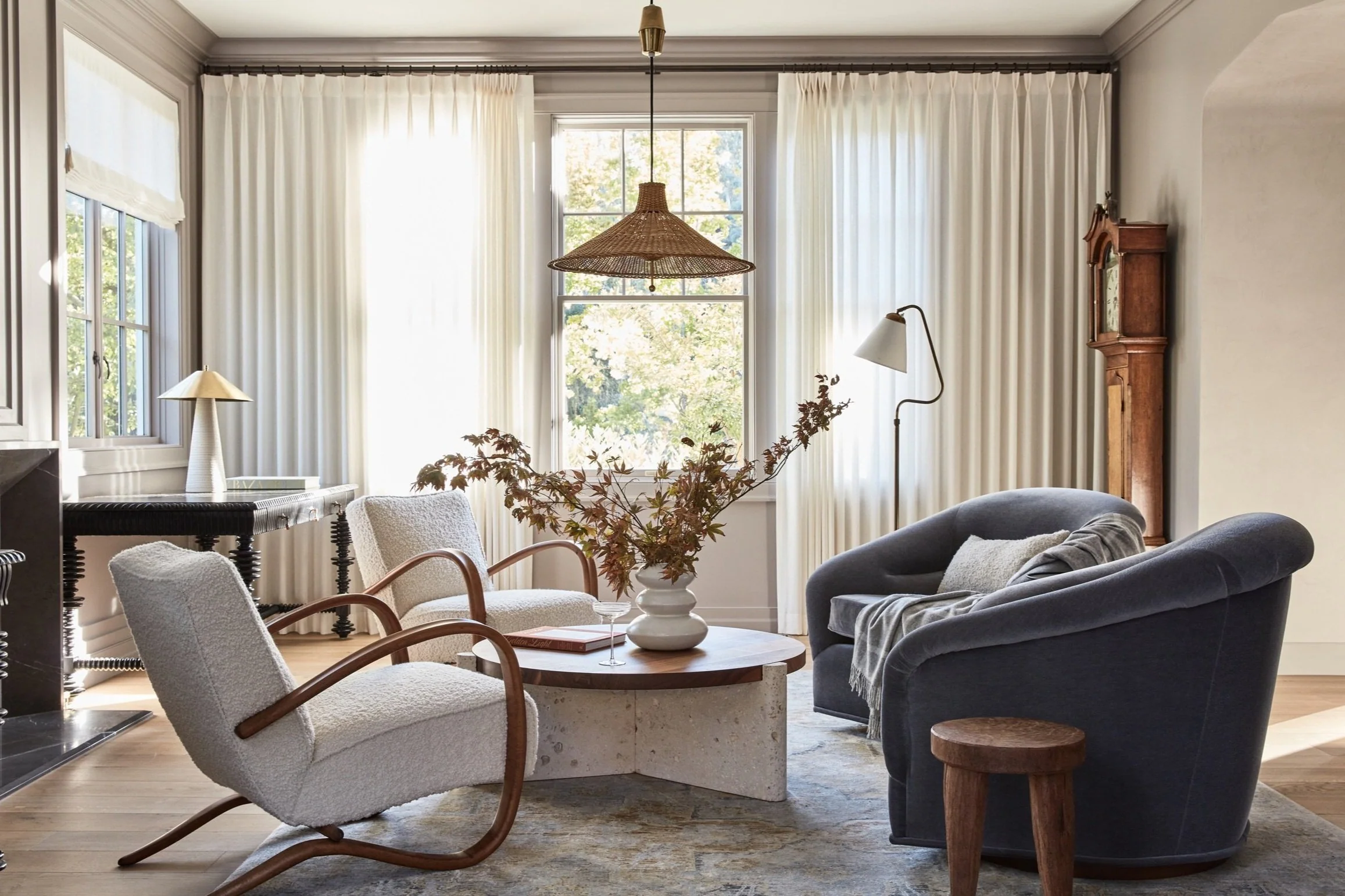 Modern living room with floor-to-ceiling cream blackout curtains, cozy armchairs, and natural light.