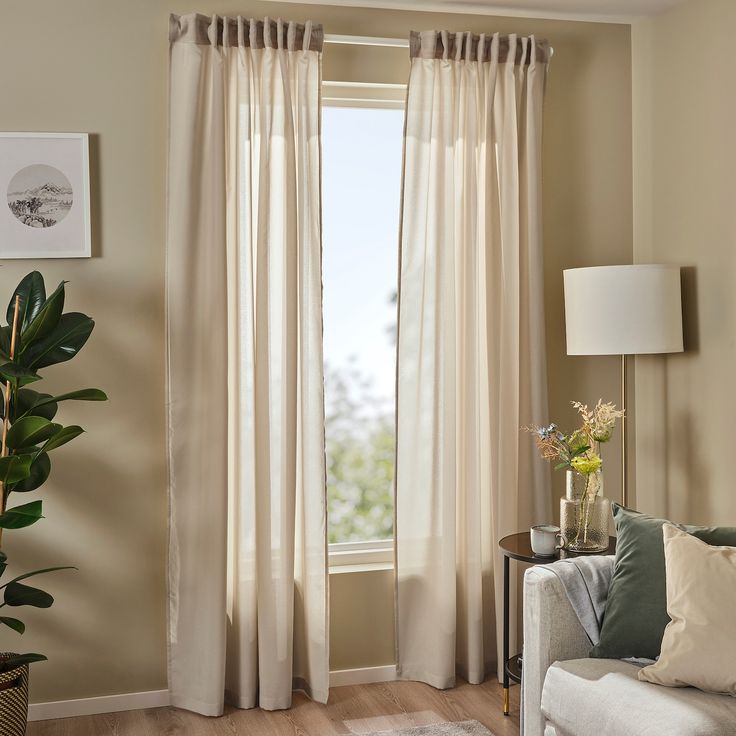 Beige blackout curtains on window in modern living room with sofa, lamp, and plant