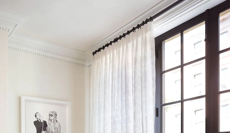 Sheer white curtain on black curtain rod in bright modern living room with large window