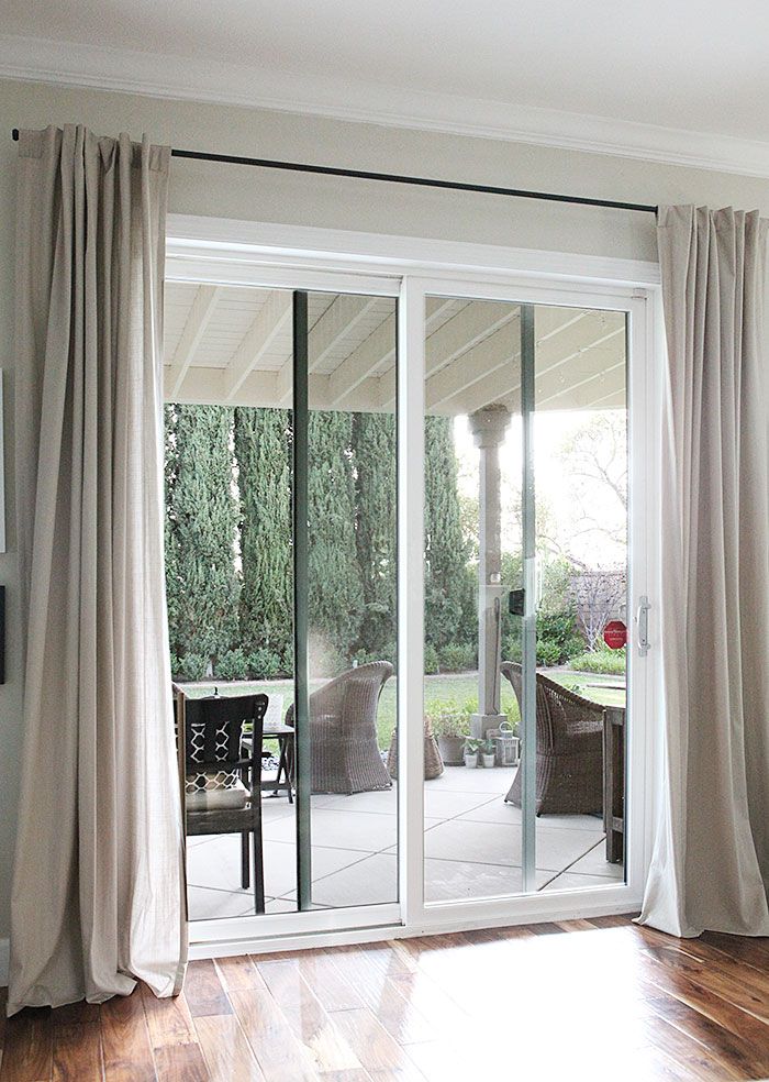 Sliding glass patio doors with beige blackout curtains and outdoor garden view