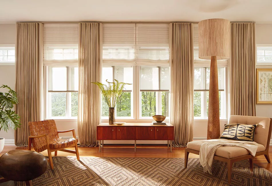 cozy sitting room with elegant floor-length curtains framing a sunlit window and neutral-toned furniture
