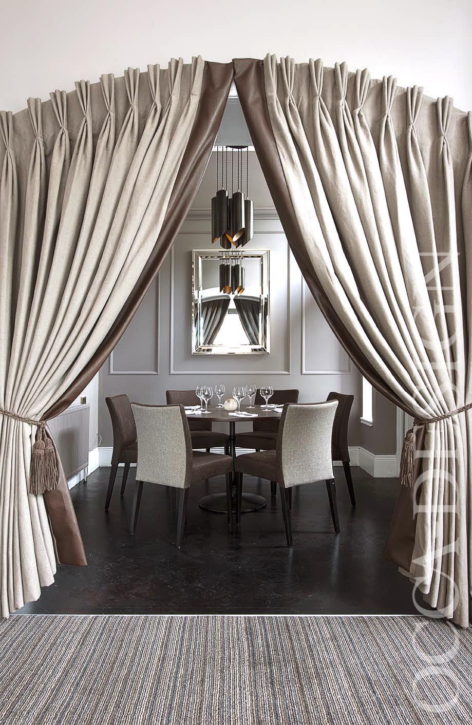 Elegant pinch pleat curtains framing a modern dining room with neutral decor
