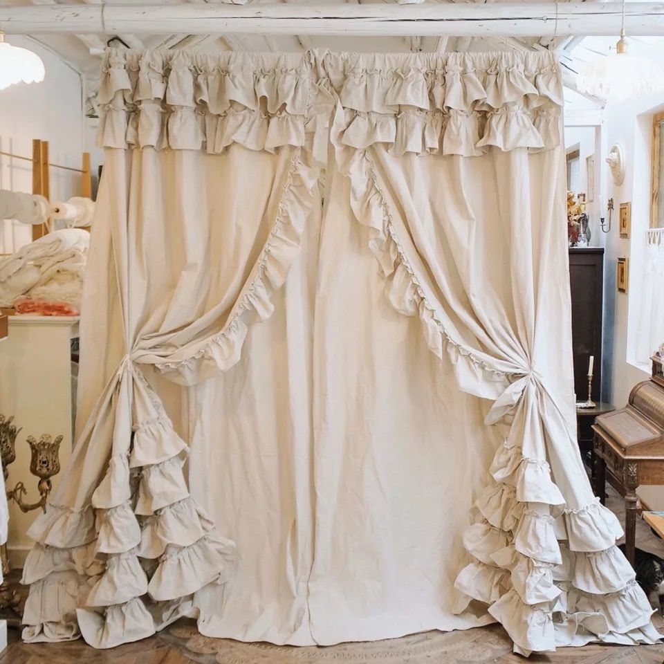 Elegant ruffled beige curtains with tiebacks, layered for a vintage-inspired window treatment.