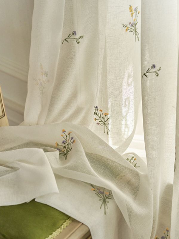 Sheer white curtain with delicate embroidered wildflowers in a sunlit room