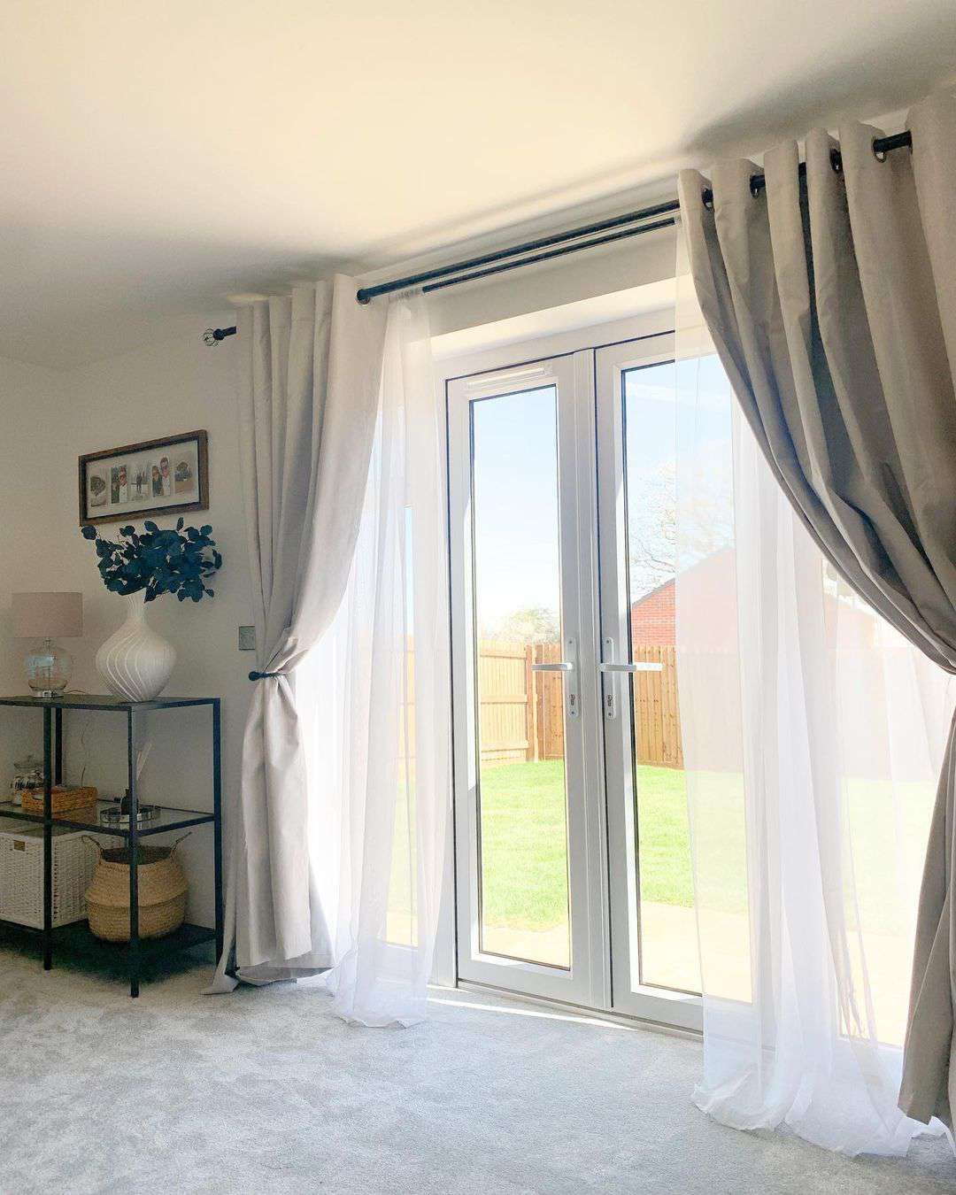 Modern living room with sheer white blackout curtains on French doors, letting in natural light.