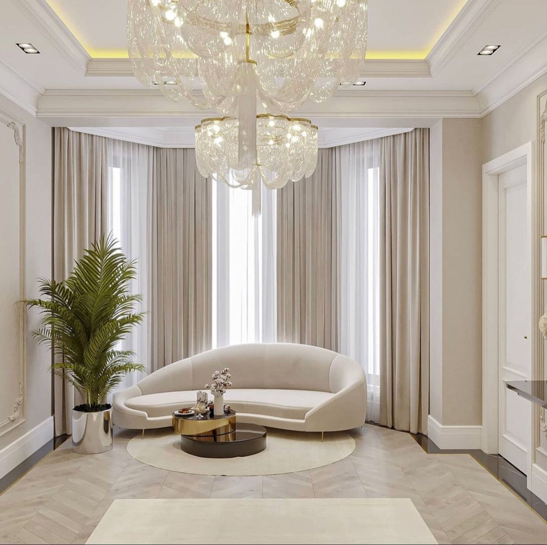 Elegant living room with beige blackout curtains, curved sofa, round coffee table, chandelier, and indoor plant
