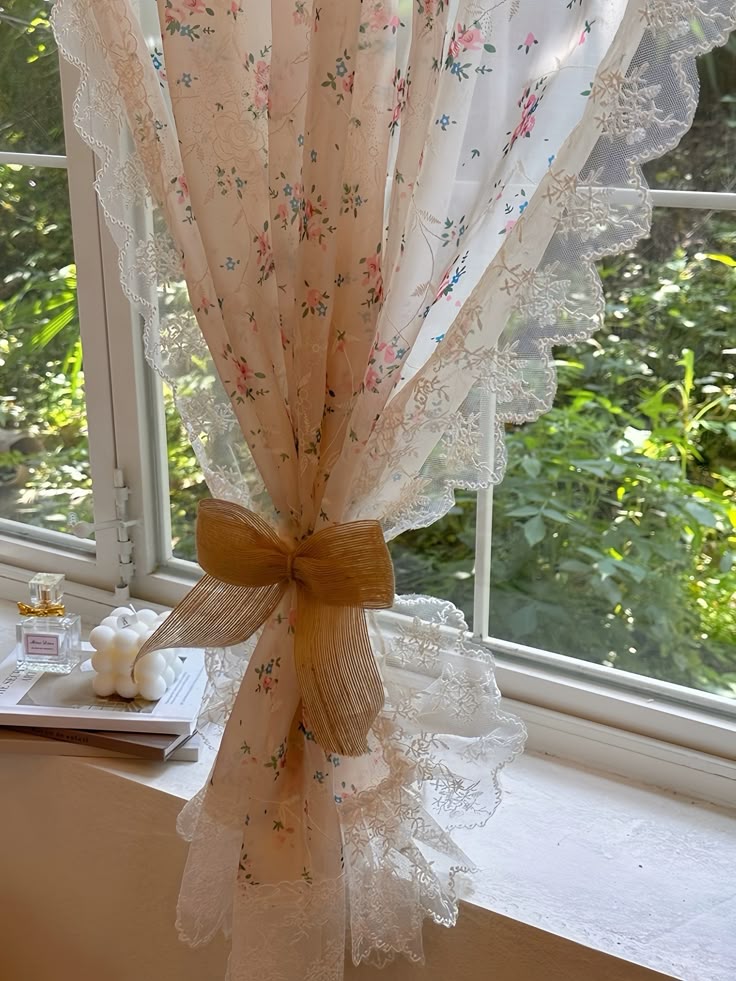 Floral lace curtain with scalloped edges and ribbon bow, tied on a sunny window.