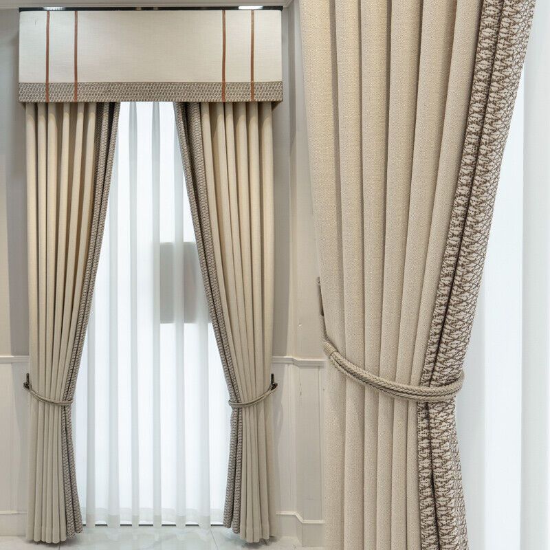 Beige blackout thermal curtains with valance and decorative tiebacks on a window