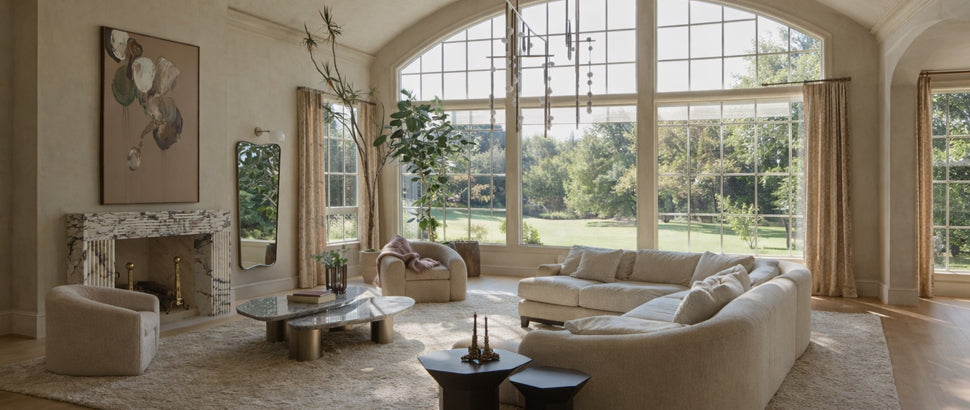 Elegant living room with large arched windows, beige sofa, curtain tracks, and garden view