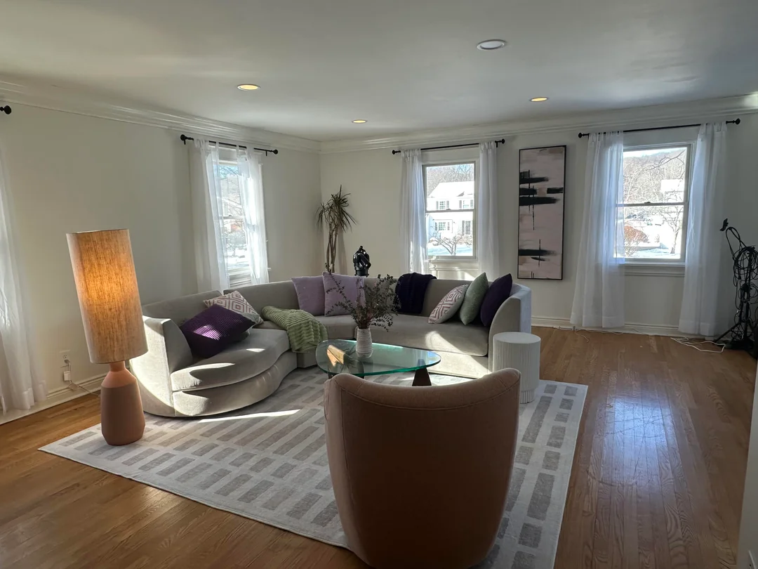 Modern living room with sheer white curtains, curved sofa, large lamp, and minimal decor
