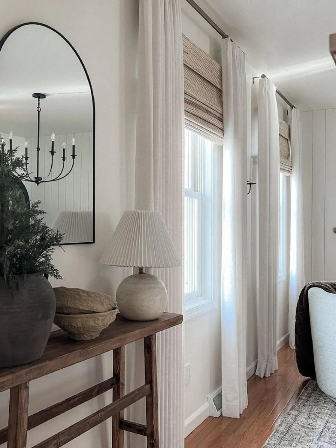 Elegant living room with white linen curtains, wood blinds, modern decor and natural light