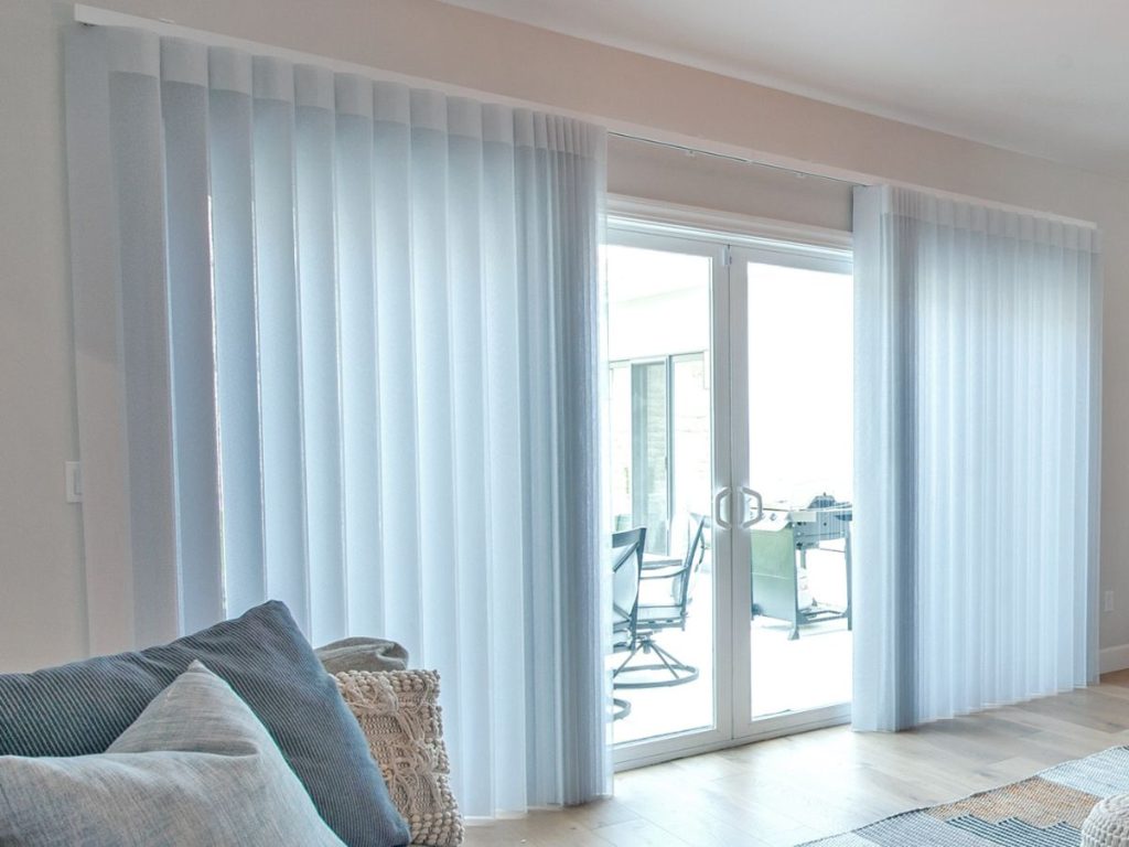 Modern living room with floor-to-ceiling sheer white vertical blinds on sliding glass doors