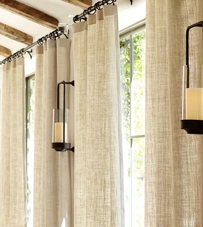 Beige blackout thermal curtains hanging on modern track in sunlit living room with lanterns