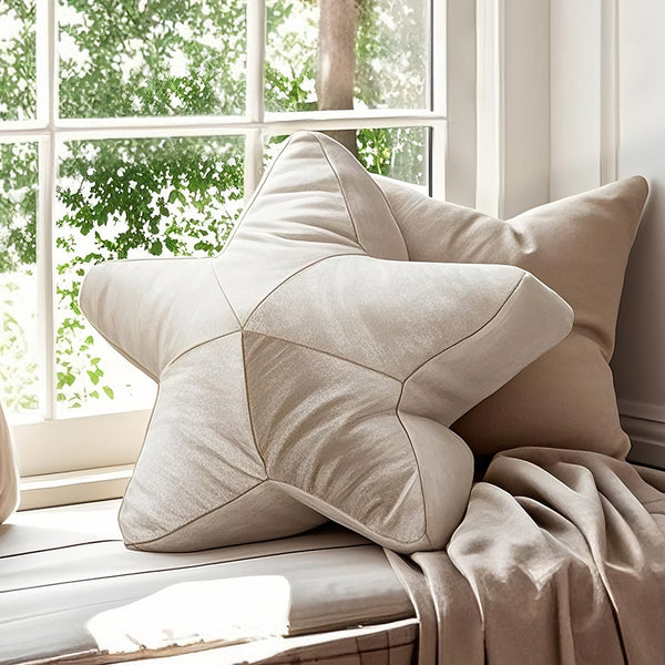 Plush star-shaped cushion on a window seat with beige pillow and soft throw blanket