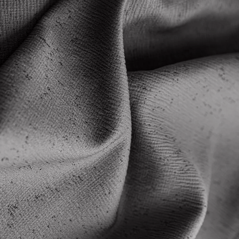 Close-up of textured gray blackout curtain fabric with subtle speckled pattern and soft folds